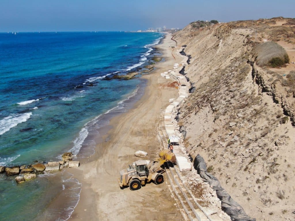 דחפור מבצע את עבודות חיזוק המדרון ובניית קיר הים בחוף תל ברוך